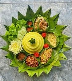 Nasi tumpeng tradisional yang lezat, disajikan dengan lauk lengkap seperti ayam goreng, perkedel, urap, telur, dan sambal.
