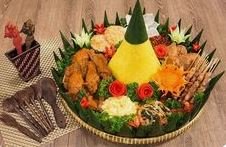 Nasi tumpeng tradisional yang lezat, disajikan dengan lauk lengkap seperti ayam goreng, perkedel, urap, telur, dan sambal.